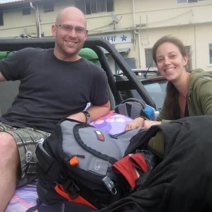 Two smiling travellers on back of ute